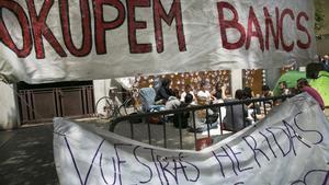 Asamblea de personas afines al movimiento ’okupa’ frente al conocido como banco expropiado’ de la calle Travessera de Gràcia -entonces blindado con paneles metálicos tras el primer desalojo-, el 29 de mayo del 2016. 