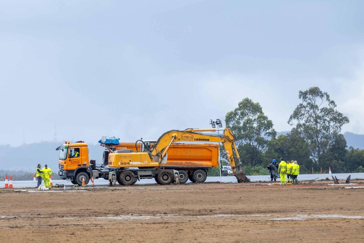 Operarios trabajando en la pista del aeropuerto de Santiago, este lunes por la tarde mientras se celebraba la reunión