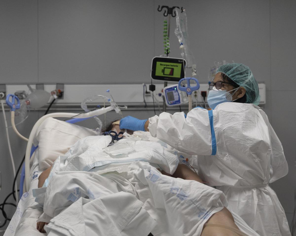 Un sanitario alrededor de un paciente ingresado en la UCI.