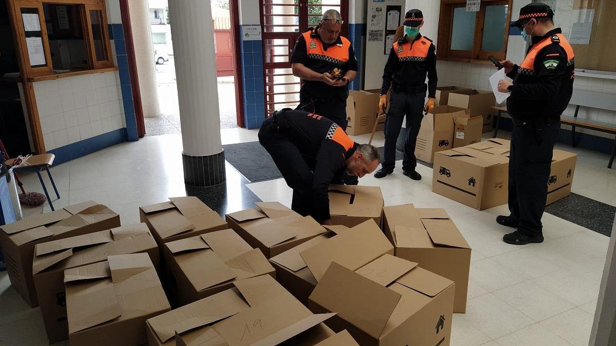 Voluntarios de Protección Civil, en el vestíbulo del instituto para recoger ordenadores que recibirán los alumnos beneficiados.