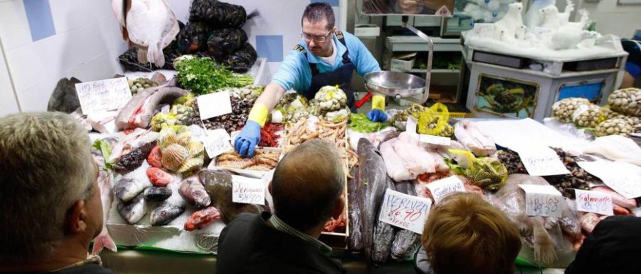 El pescadero Juan Manuel Ferrero prepara un pedido de langostinos observado por un grupo de clientes.