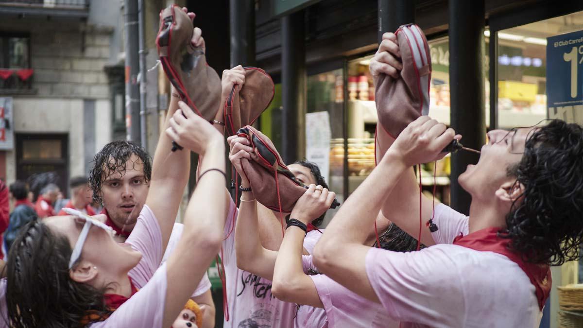 Varias personas beben de una bota de vino en una calle de Pamplona, el día de la inauguración de las Fiestas de San Fermín 2022.
