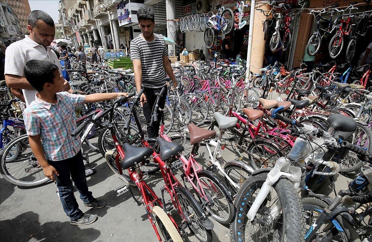 un padre y su hijo iraquíes inspeccionan las bicicletas en un mercado en el barrio al-Sadreyh, en el centro de Bagdad.
