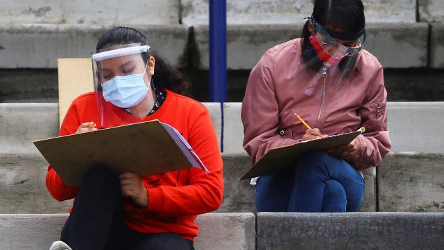 Estudiantes de México realizan un examen en el exterior y protegidas con pantallas.