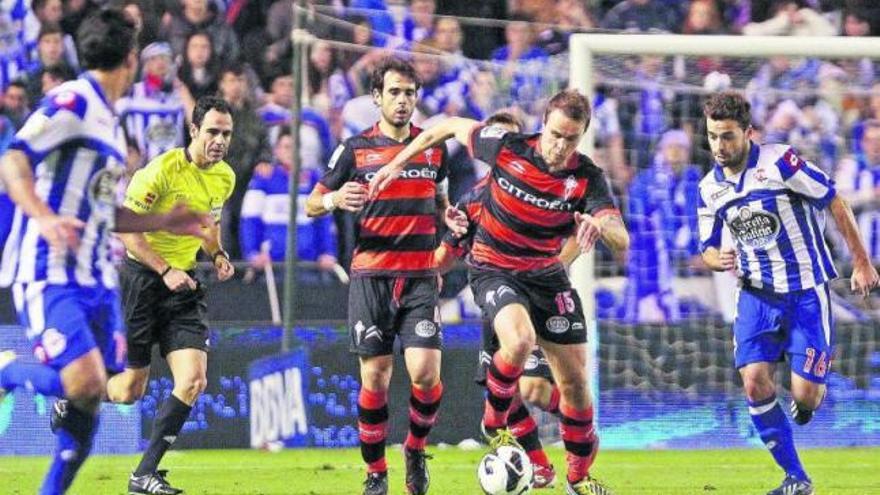 Demidov intenta salir con el balón controlado, seguido de cerca por Oubiña, en Riazor.  // Marta G. Brea