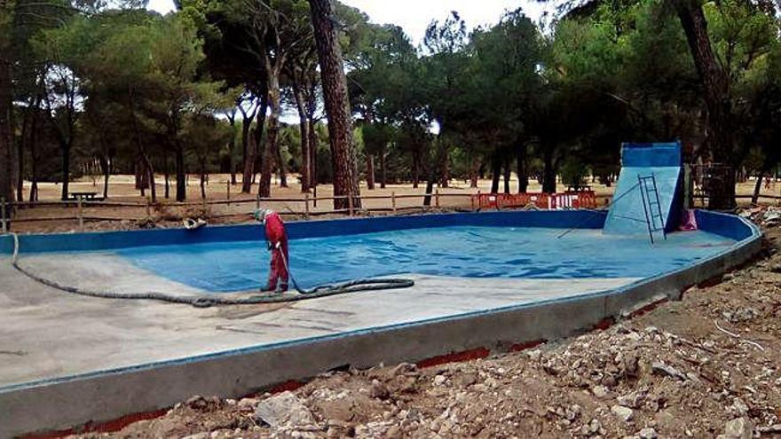 Un operario pinta el estanque de Félix Rodríguez de la Fuente, tras su remodelación, en la que se aprecia la nueva cascada. Debajo, operarios que durante un mes limpiarán maleza y ramas caídas en Valorio.