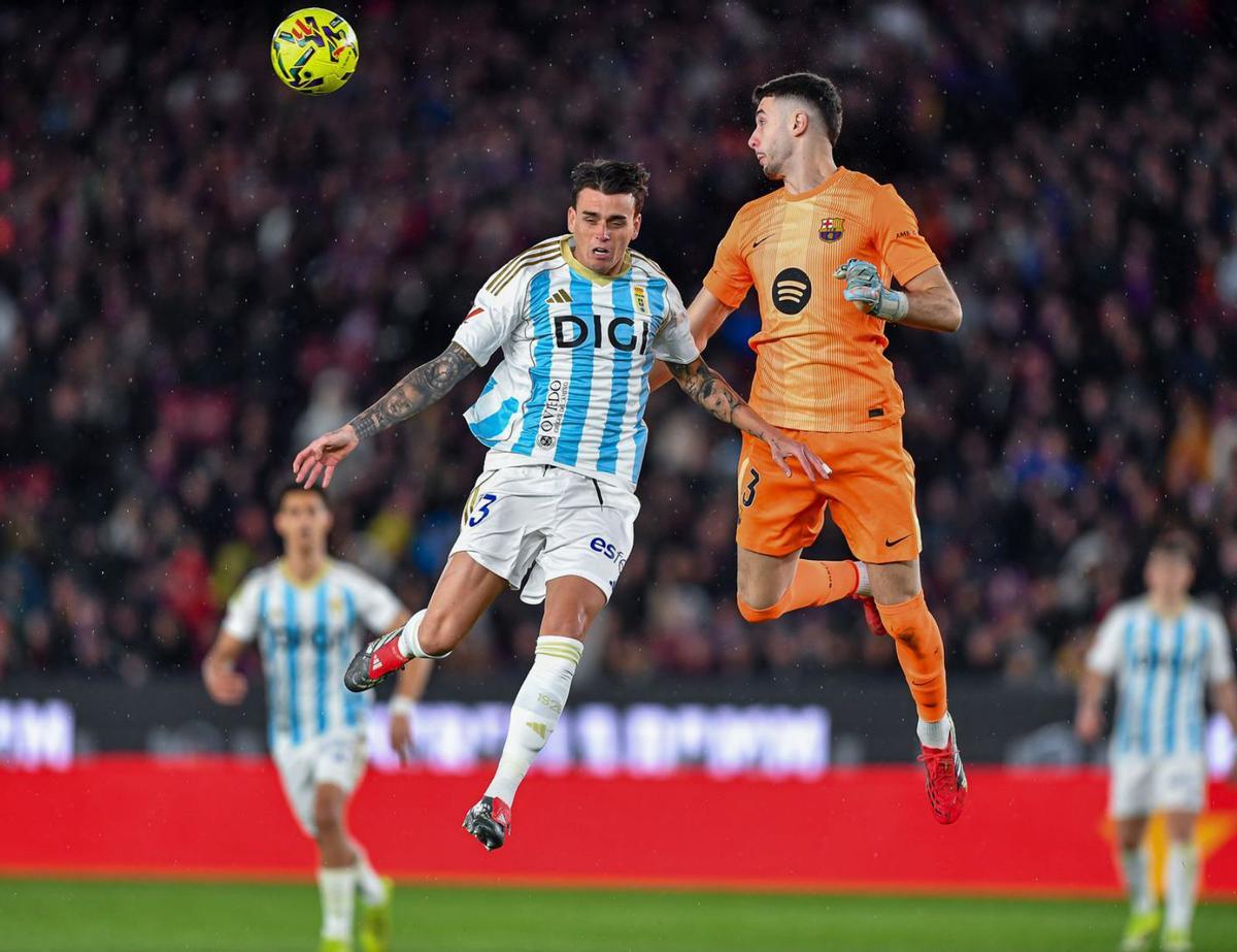 Fonseca salta a disputar un balón con Joan García durante el duelo del Oviedo ante el Barça en el Camp Nou. | SERGIO ROS / FACTORÍA 9
