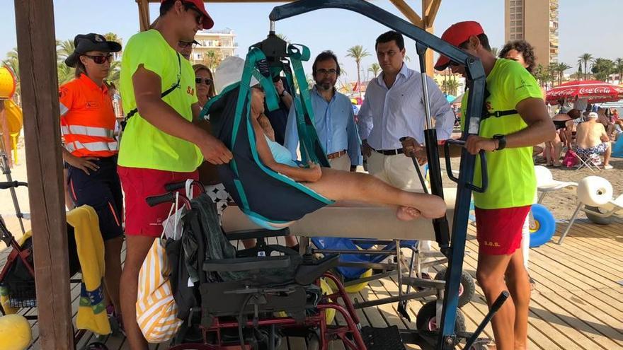 Una mujer se dispone a utilizar la silla anfibia ante la mirada del consejero y el alcalde de San Javier. L. O.