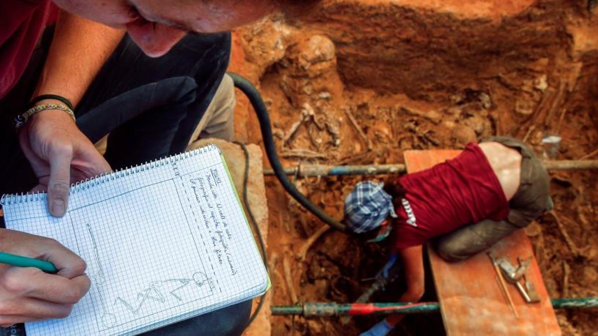 Un trabajador anota los datos que su compañera extrae de una fosa excavada durante la dictadura franquista.