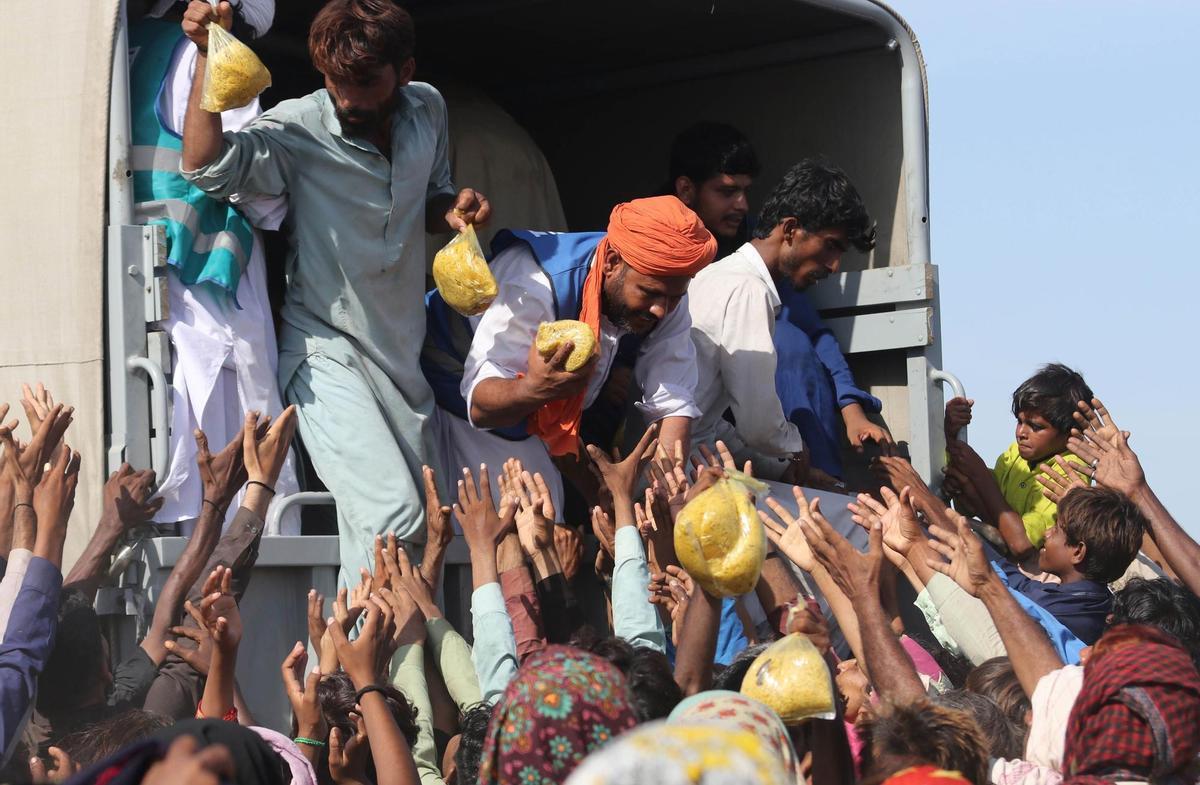 Sehwan (Pakistan), 01/09/2022.- People affected by floods receive aid in Sehwan, Sindh province, Pakistan, 01 September 2022. According to the National Disaster Management Authority (NDMA) on 27 August, flash floods triggered by heavy monsoon rains have killed over 1,000 people across Pakistan since mid-June 2022. More than 33 million people have been affected by floods, the country’s climate change minister said. (Inundaciones) EFE/EPA/REHAN KHAN