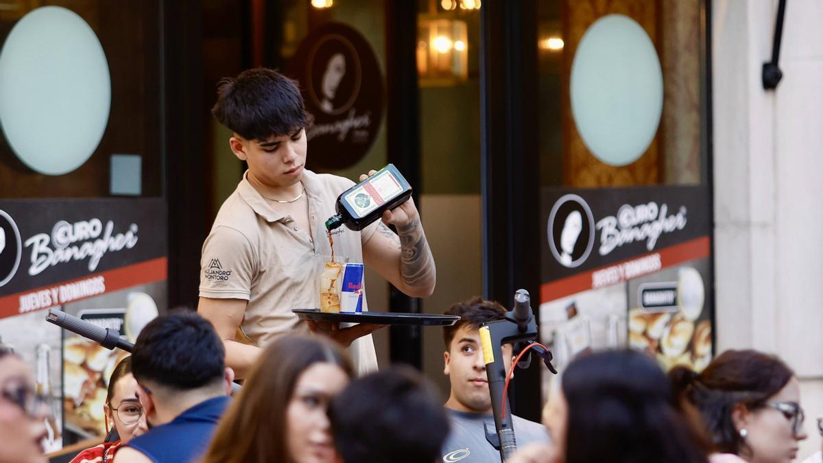 Un joven trabajando trabajando en la terraza de un bar.