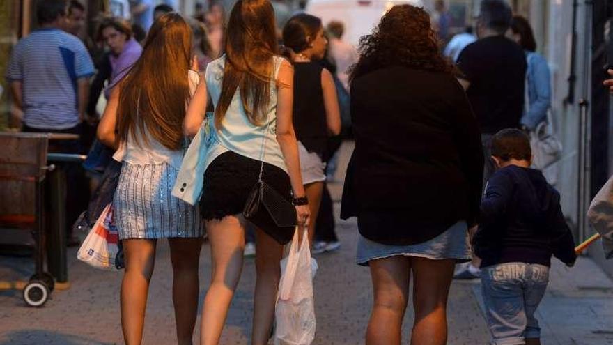 Dos jóvenes con bolsas con botellas por la calle en una ciudad gallega.