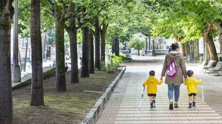 Una madre con dos niños con impermeable y paraguas. // Carlos Peteiro