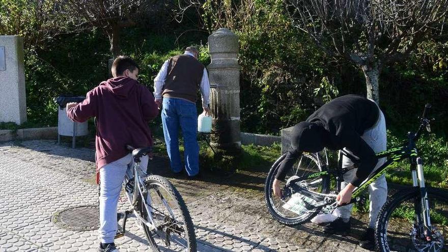 Vecinos de Bueu llenan ayer recipientes con agua en la conocida como Fonte do Cura, en la calle Ramón Bares. // Gonzalo Núñez