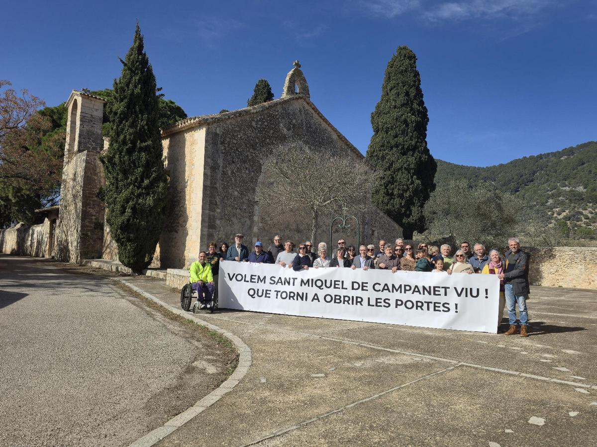 Representantes de la cooperativa y vecinos exhiben una pancarta a favor de la reapertura de Sant Miquel.