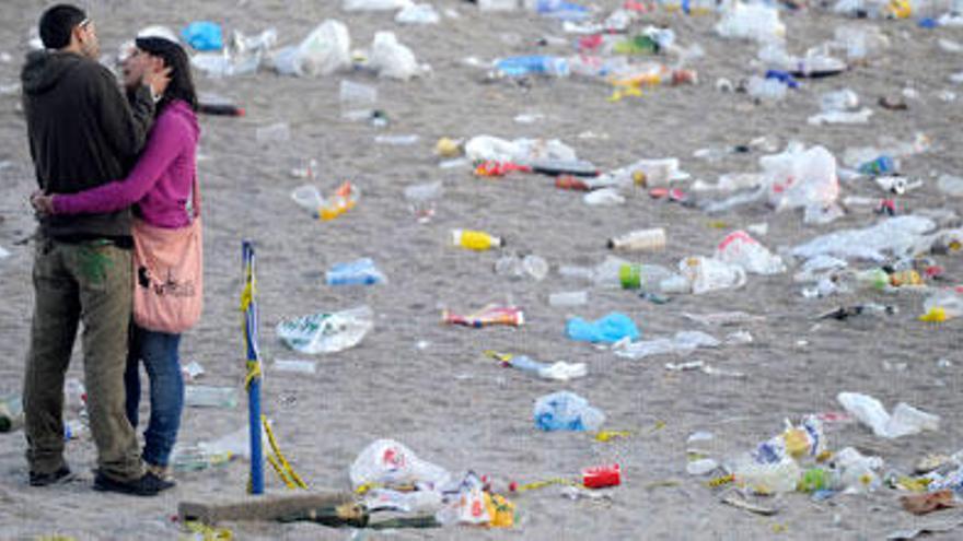 Pareja ante la basura acumulada en la playa de Riazor.