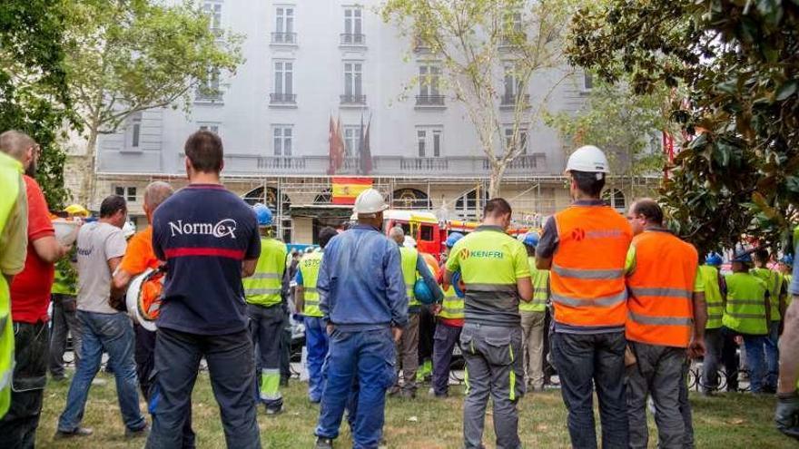 Varios obreros observan la actuación de los equipos de emergencias en el Hotel Ritz tras el siniestro.