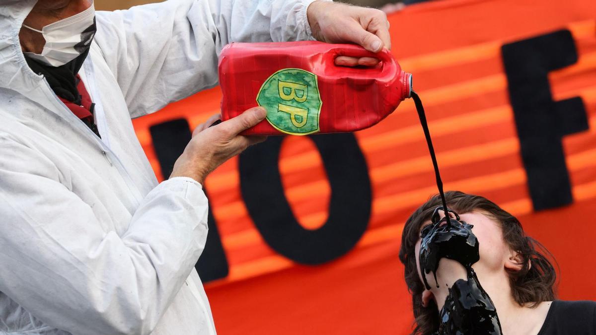 Una mujer simula beber combustible en una protesta por el cambio climático.