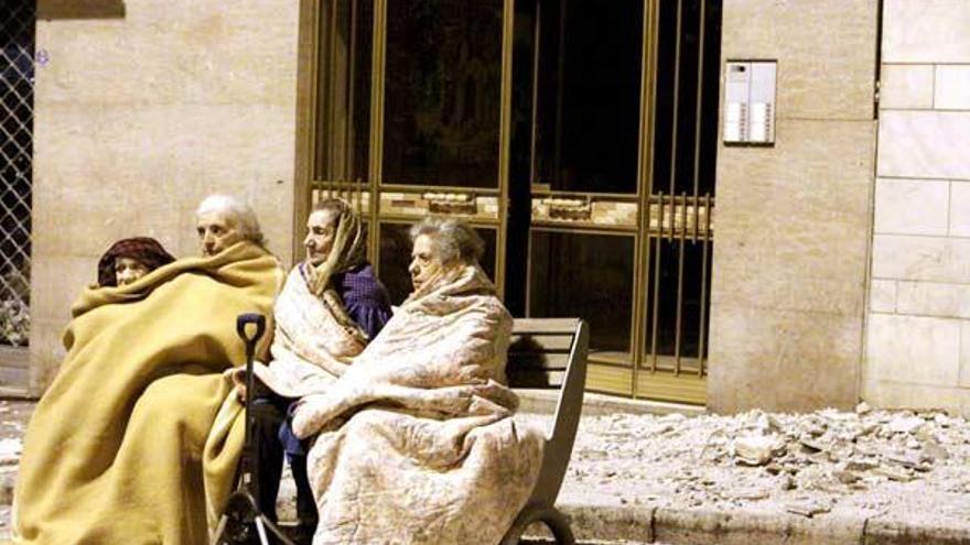 Cuatro ancianas sentadas en el banco de una calle junto a los escombros provocados por el terremoto