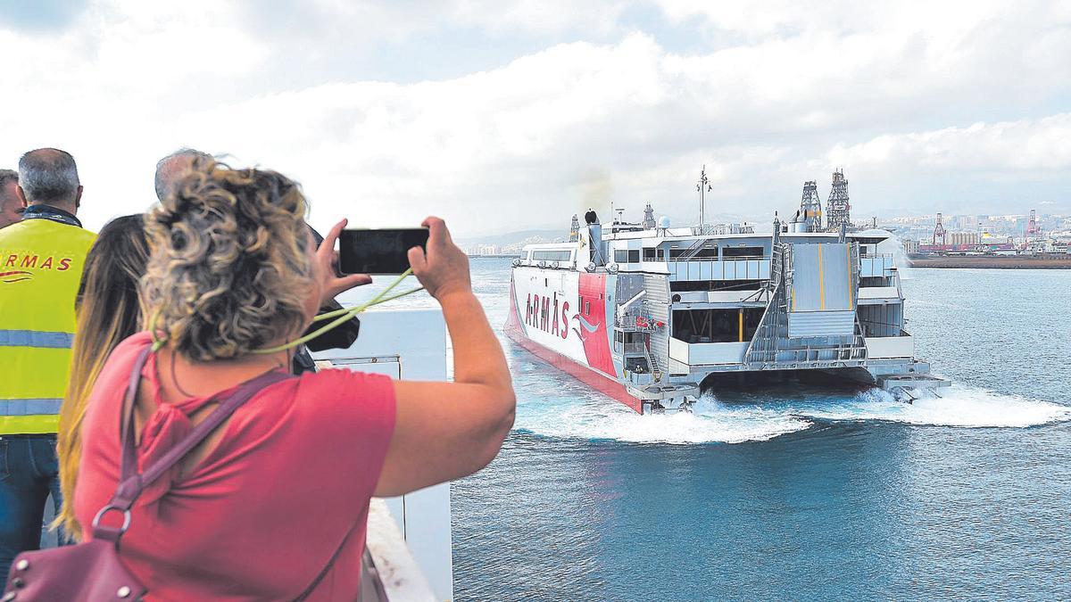 Una mujer fotografía un catamarán de la Naviera Armas a su salida del puerto.