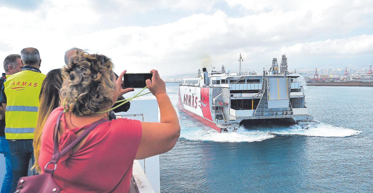 Una mujer fotografía un catamarán de la Naviera Armas a su salida del puerto.