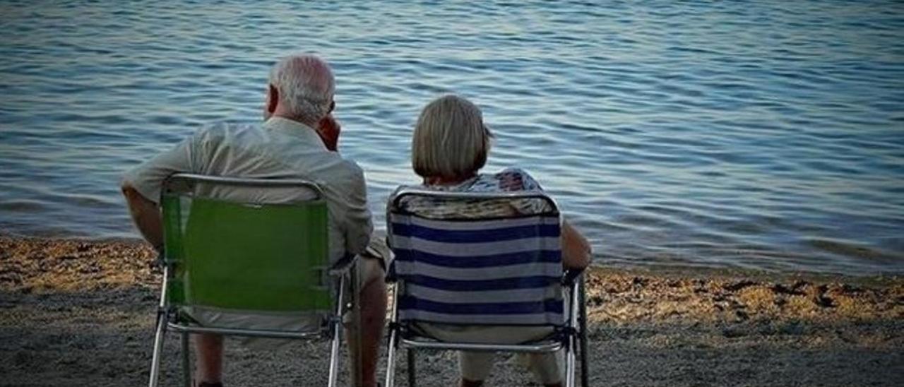 Una pareja de jubilados descansa en la playa.