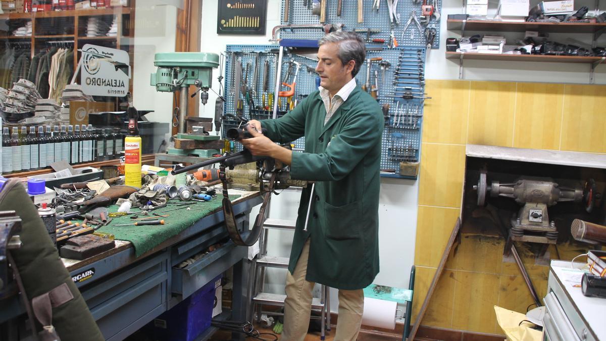 Alejandro Galán ajusta la mira telescópica de un rifle en su taller.