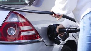 Una mujer echa gasolinera autoservicio a su vehículo.