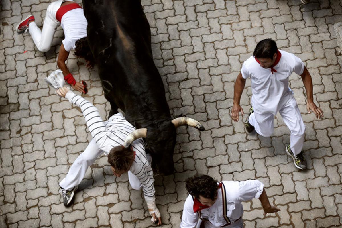 Imatge del transcurs del setè ’encierro’ on un corredor gairebé és banyegat per un dels toros.