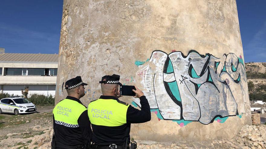 Miguel y Juan toman una imagen del grafiti que hay en la Torre Vigía de las Palomas, en La Araña.