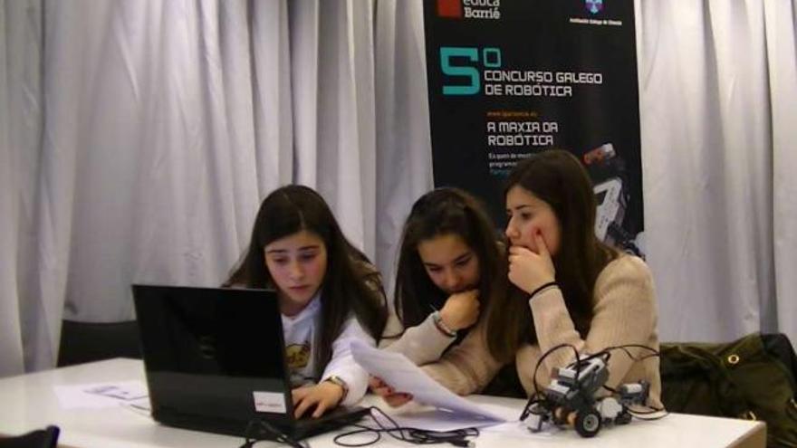 Tres alumnas intentan resolver el problema en el ordenador, con el pequeño robot a la derecha.  // F. Barrié