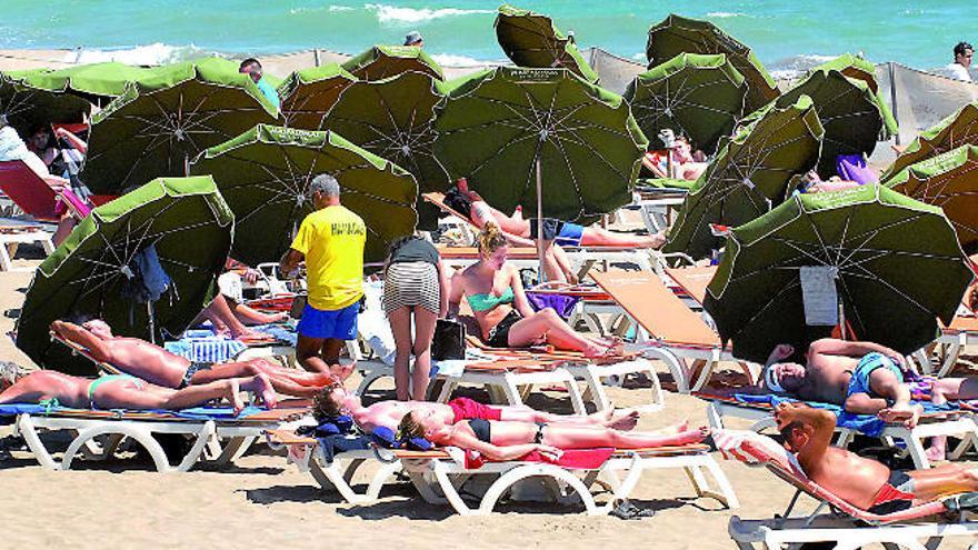 Turistas tumbados al sol en Playa del Inglés.