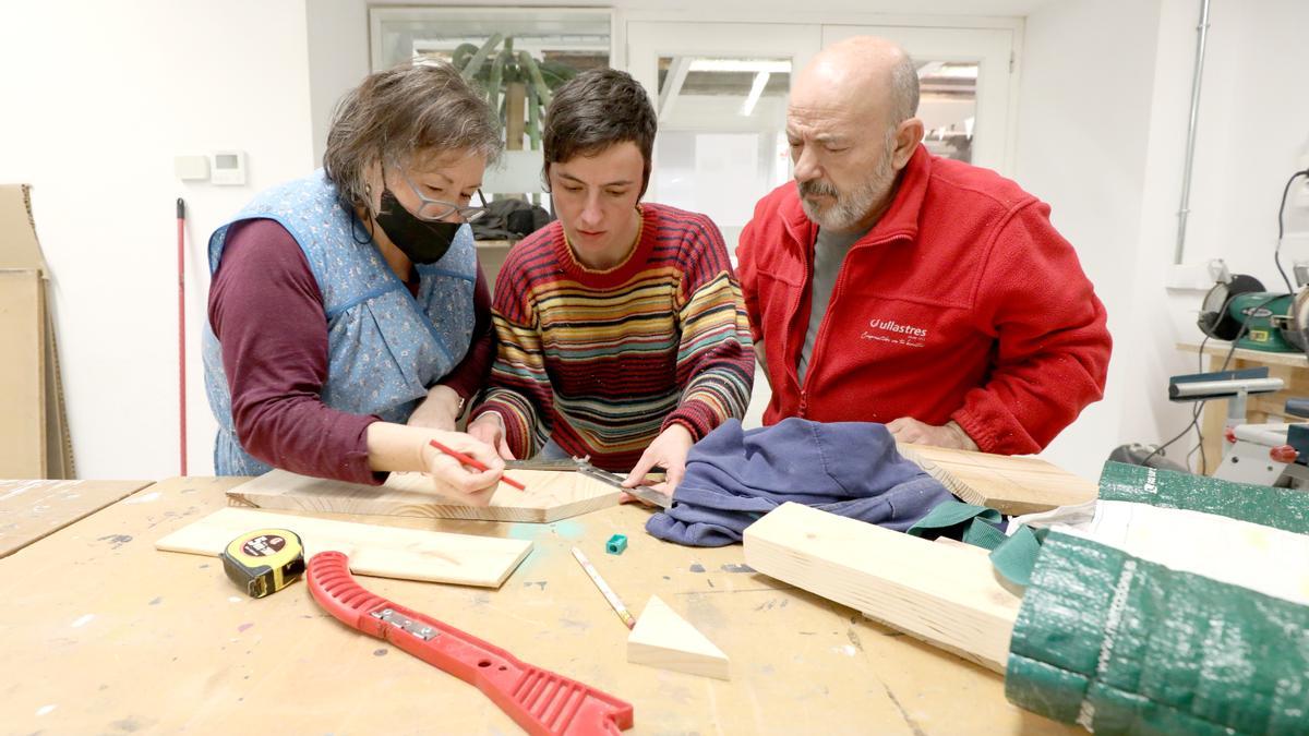 Vázquez, en el centro, ayuda a una pareja a cortar unas maderas para hacer una caseta de pájaros de decoración.