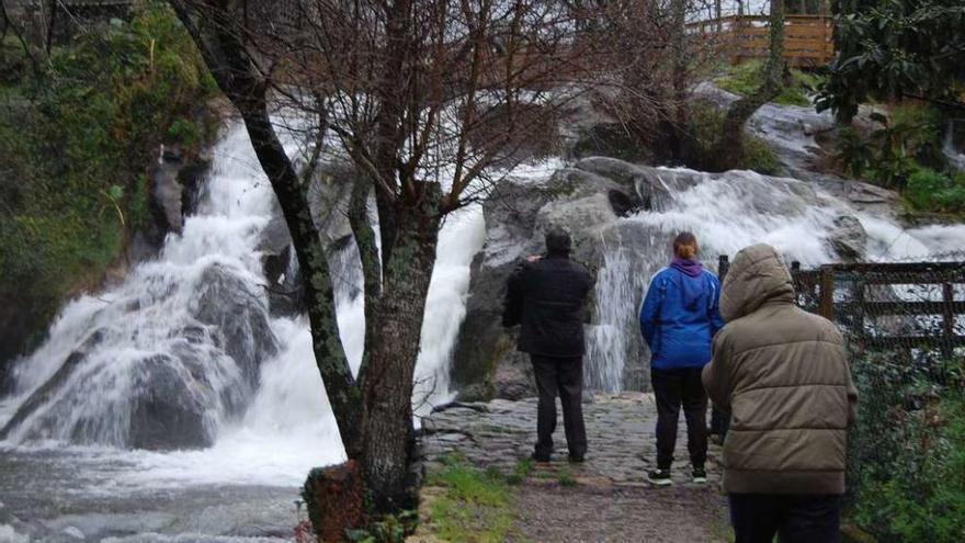 Unas personas contemplan la cascada de A Feixa, ayer, en el río Alvedosa a su paso por Redondela. // FdV