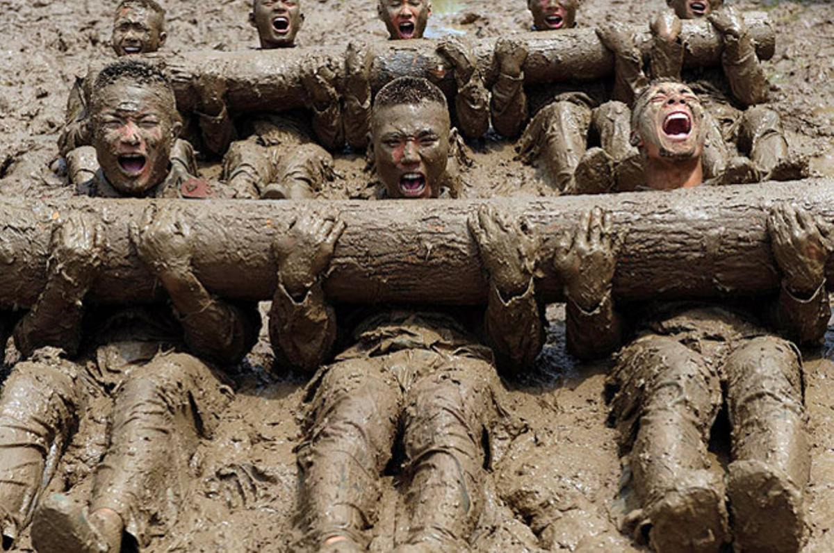 Agents de la policia paramilitar, coberts de fang, durant un exercici d’entrenament amb troncs, a la ciutat de Chuzhou, al centre de la Xina.