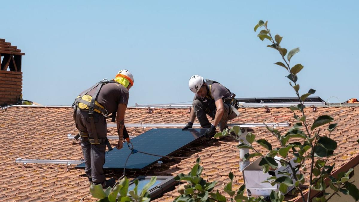 Dos trabajadores de Solarprofit instalan una placa solar fotovoltaica en un tejado.