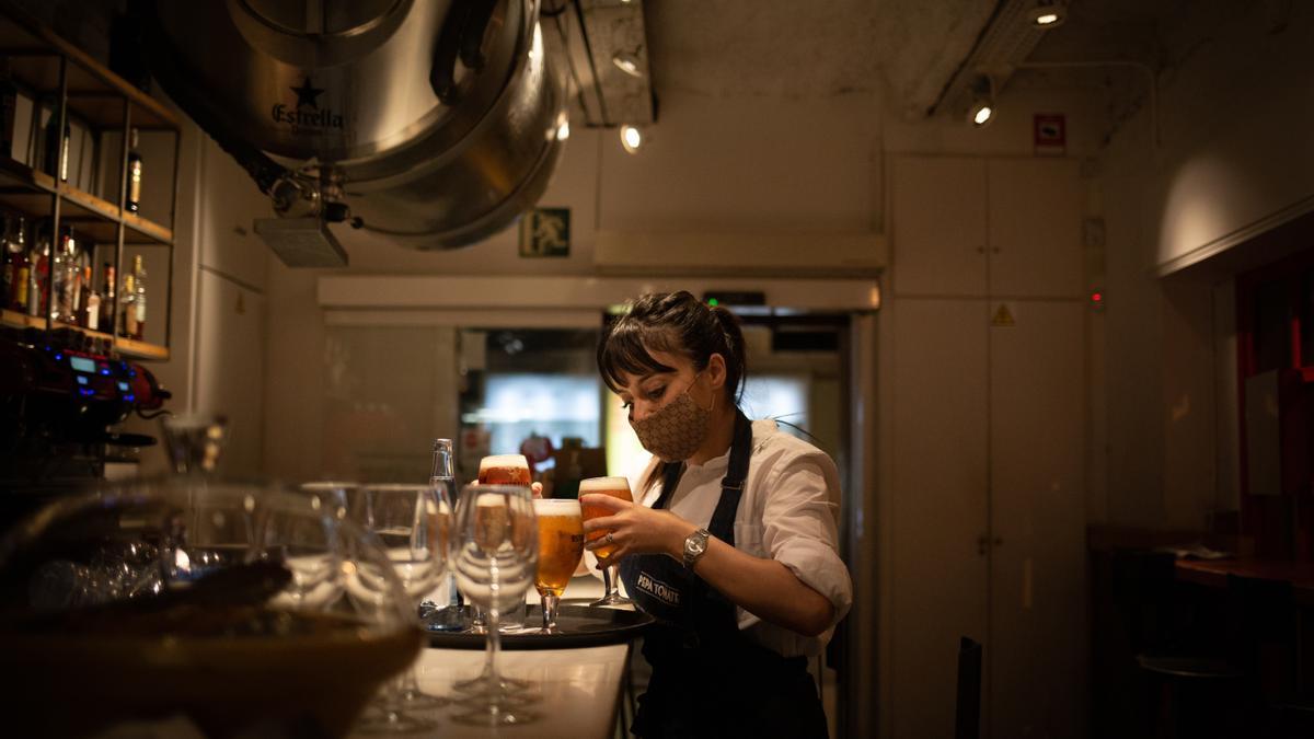 Una camarera sirve una cerveza en el interior de un bar.