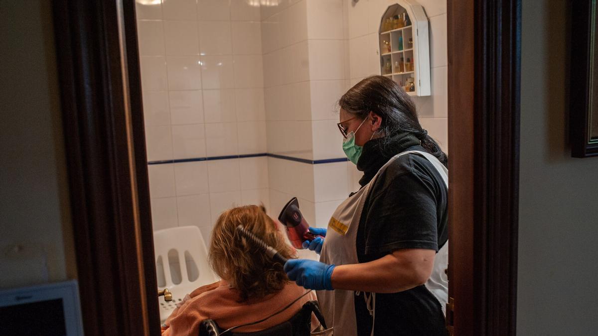 Una trabajadora de ayuda a domicilio atiende a una mujer en su casa.
