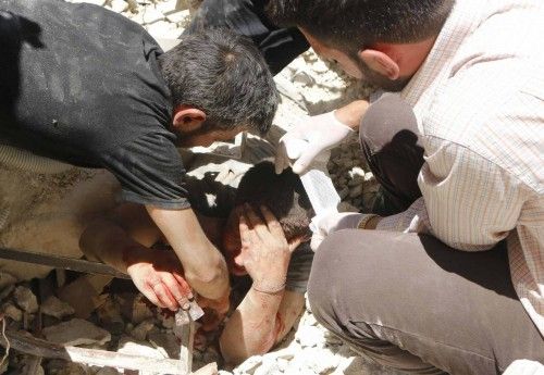 A man tries to pull a casualty from under the rubble of collapsed buildings at a site hit by what activists said was a barrel bomb dropped by forces loyal to Syria's President al-Assad in Aleppo