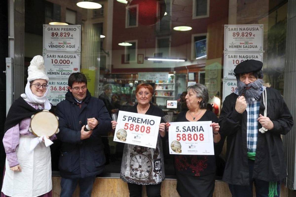Las loteras María Jesús (d) y Begoña junto al Olentzero (d) celebran el reparto del número 58808, quinto premio de la lotería de Navidad, que le ha tocado al número 58808, en un punto de venta de la calle Castaños de la capital vizcaína. EFE