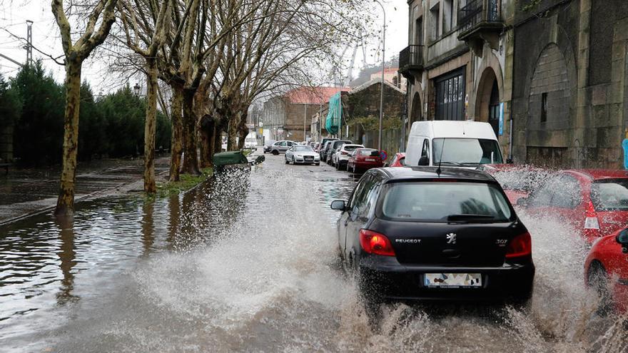 Un vehículo circula por una calle de Vigo cubierta de agua. // Alba Villar