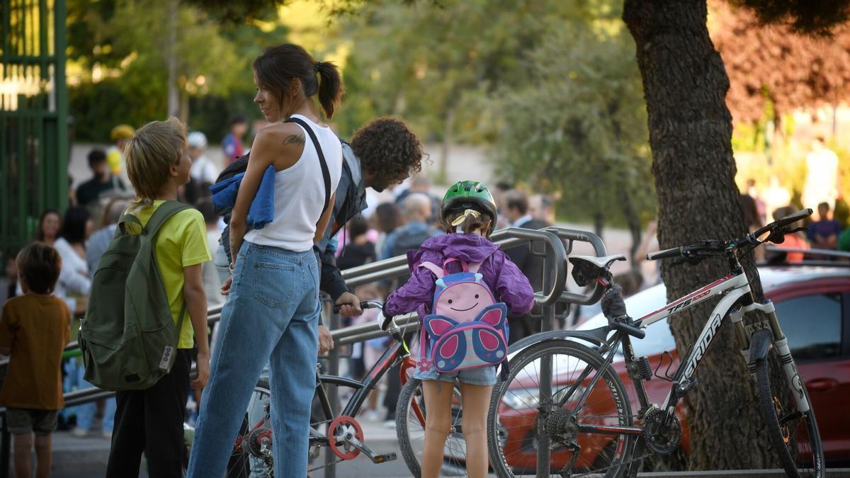 Un amadre espera con sus hijos en la puerta del colegio.
