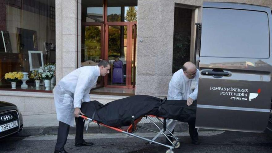 Dos trabajadores de los servicios funerarios de Pontevedra introducen en el furgón el cuerpo sin vida de Manuel Ángel Rivas Muiños.