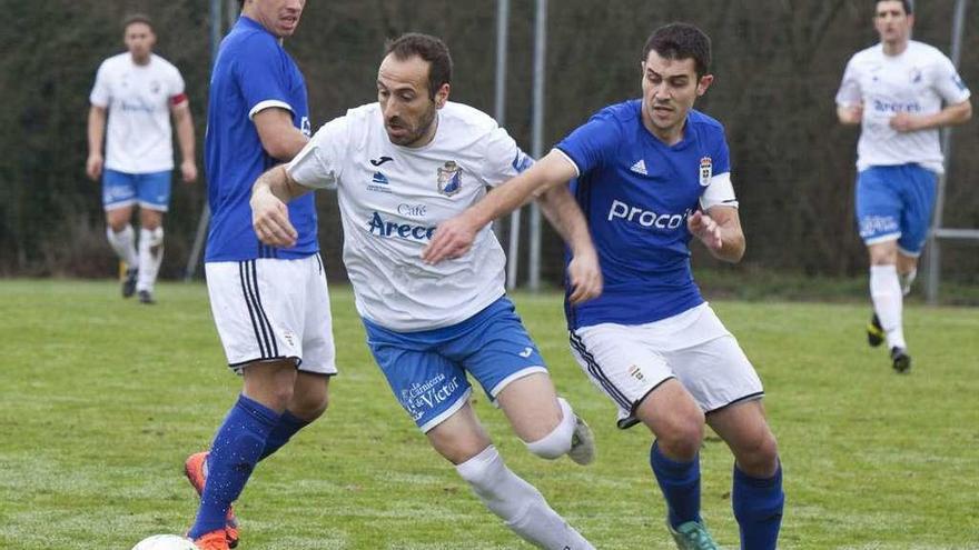 El jugador del Mosconia Rubén Valdés entre Steven, a la izquierda, y Lucas, del Oviedo B.