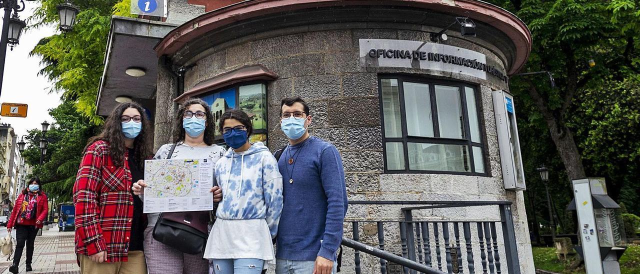Por la izquierda, Saray Lerma, María Fernández, Nerea Lerma y Óscar Lerma posan con un mapa de Oviedo junto a la Oficina de Turismo del Escorialín, que ayer reabrió sus puertas tras medio año de cierre. | Nazaret Quintas