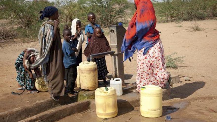 Un grupo de personas saca agua de una fuente