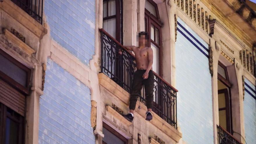 El joven, colgado de una mano del balcón del edificio.