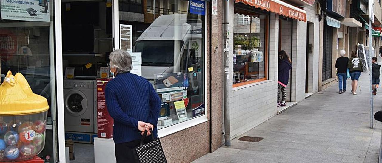 Vecinos a las puertas de comercios en Chapela. |   // FDV