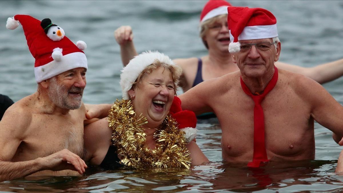 Miembros del club de natación de hielo Berliner Seehunde Berlin Seals se dan un chapuzón en el lago Orankesee en Berlín como parte de su tradicional sesión de natación en hielo navideño