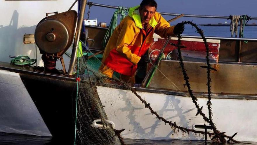 Un pescador trata de liberar sus redes de una cuerda de cultivo de mejillón tirada en la ría. // Iñaki Abella